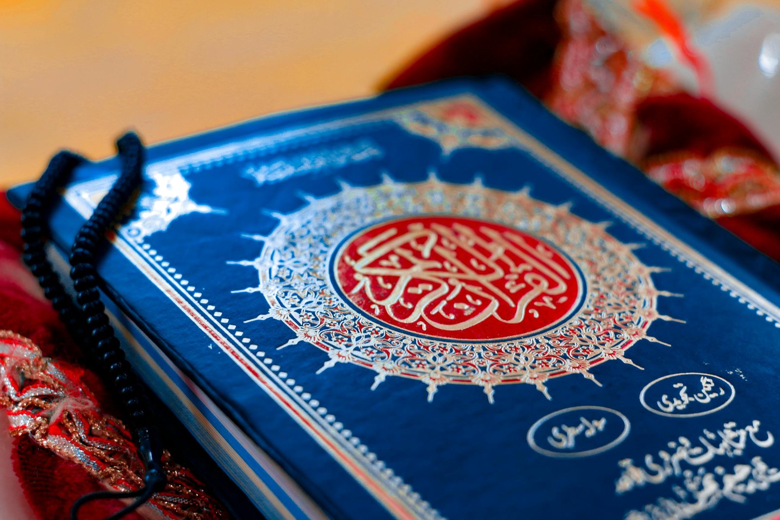 A close-up photograph of the Holy Quran with prayer beads, depicting Islamic spirituality.